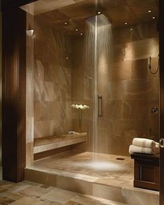 a bathroom with a large shower and tiled flooring, along with a wooden stand up shower head