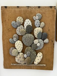 a wooden plaque with rocks in the shape of flowers on it and a pair of scissors next to it