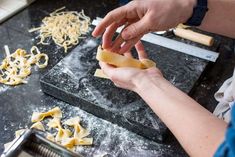 a person is kneading some food on top of a black table with other items