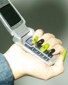 a person holding a cell phone in their hand with yellow and black nail designs on it