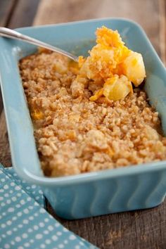 a blue bowl filled with oatmeal topped with fruit next to a spoon