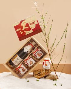 a bottle of wine in a gift box next to a small tree branch and cookies