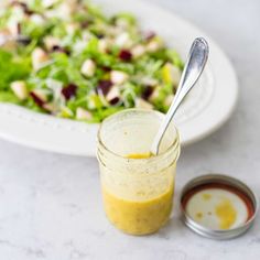 a salad with dressing in a jar next to it