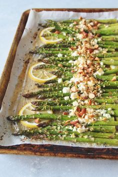 asparagus with lemons, almonds and parmesan cheese on a baking sheet