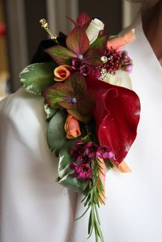 a close up of a person wearing a suit and tie with flowers on it's lapel