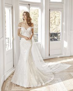 a woman in a wedding dress standing by a window