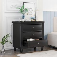 a black night stand with three drawers and a mirror on it in a living room