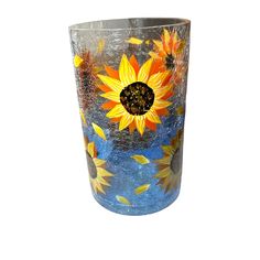 a glass vase with sunflowers painted on the side and blue sky in the background