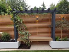 a wooden bench sitting under a pergolated trellis next to two planters