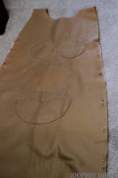 a piece of brown paper on the floor with circles drawn on it and holes in the fabric