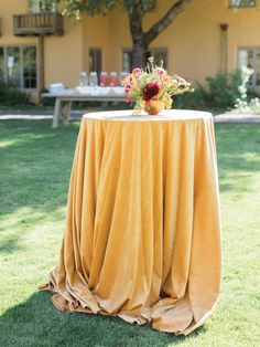 a table with a yellow cloth and flowers on it