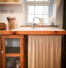 a kitchen with a sink, dishwasher and cupboards in front of a window