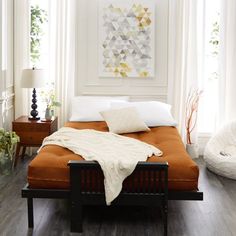 an orange bed with white pillows and blankets