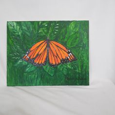 an orange butterfly sitting on top of green leaves