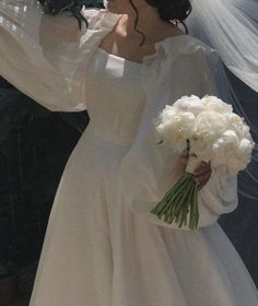 a woman in a white dress holding a bouquet of flowers