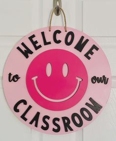 a pink welcome to classroom sign hanging on a white door with the words welcome to classroom