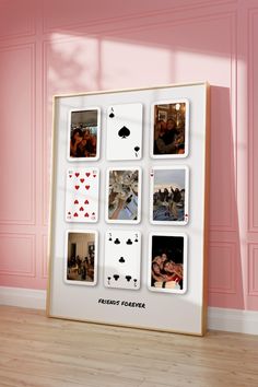 a white frame with playing cards on it in front of a pink wall and hardwood floor