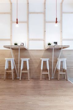 three white stools sitting in front of a counter