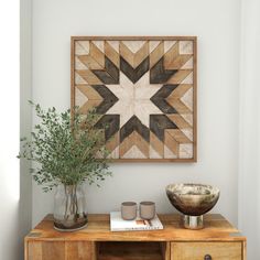 a wooden table topped with a vase filled with green plants next to a star shaped wall hanging