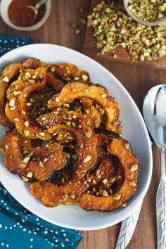 a white bowl filled with sliced bananas and nuts on top of a wooden table next to silverware