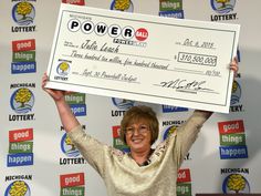 a woman is holding up a large check