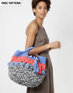 a woman carrying a crocheted bag in blue, pink and black with an orange stripe