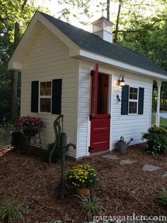 a small white shed with a red door