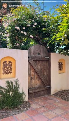 a wooden gate with two decorative designs on the wall and behind it is a brick walkway