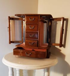 an antique wooden jewelry box sitting on top of a white table next to a mirror