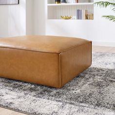 a brown leather ottoman sitting on top of a rug