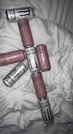 six empty cans are arranged in the shape of a cross on a bed with white sheets