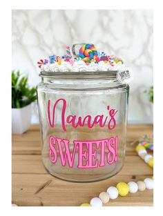 a glass jar filled with white frosting and sprinkles on top of a wooden table