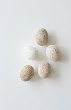 four white and gray rocks sitting on top of a white table next to each other