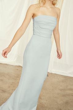 a woman in a strapless blue dress poses for the camera with her hand on her hip