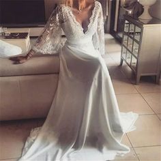 a woman is sitting on a couch wearing a white wedding dress with long sleeves and an open back