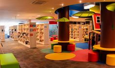 the children's library is brightly decorated with bookshelves and colorful stools