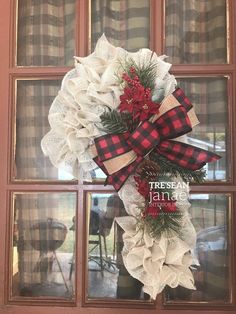 a christmas wreath on the front door of a house that is decorated with burlocks and pine cones