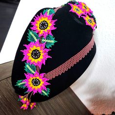 a black hat with pink and yellow flowers on the brim is sitting on a table