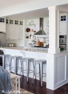 a kitchen with white cabinets and bar stools