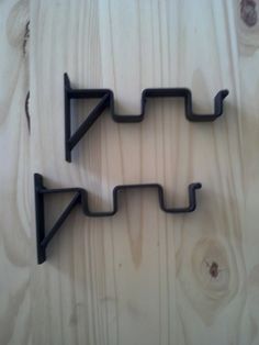 two black metal brackets on a wooden surface