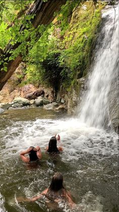 two people in the water near a waterfall