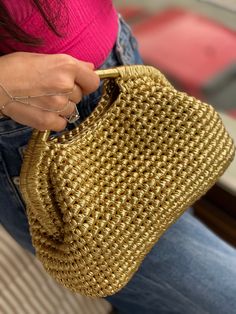 a woman is holding a straw purse in her hand