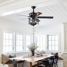 a dining room table with four chairs and a fan hanging from the ceiling above it