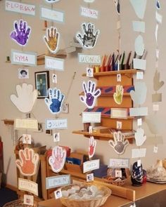 several handprints are hanging on the wall in front of a table with other items