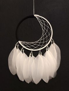 a white dream catcher hanging on a black wall