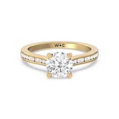 a yellow gold engagement ring with diamonds on the band and a round cut diamond in the center