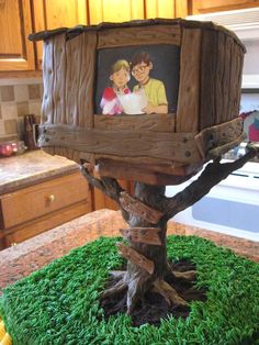 there is a cake made to look like a tree house with two people on it