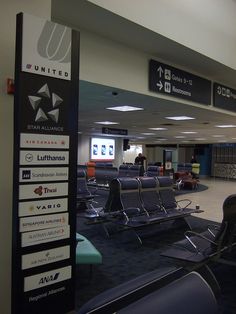 an airport terminal with many chairs and signs