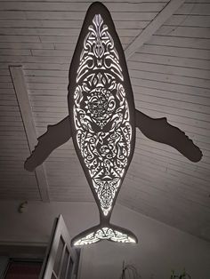 a fish shaped light hanging from the ceiling in a room with white walls and ceilings