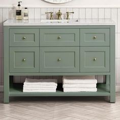 a bathroom vanity with two towels stacked on it's side and a round mirror above the sink